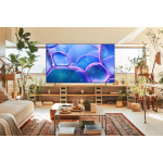 Living room with a large flat-screen TV on a wooden console, surrounded by potted plants and natural light.